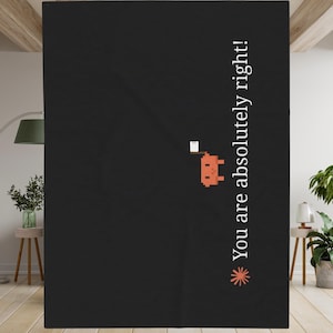 May include: A black rectangular blanket featuring a small orange pixelated creature holding a white square object. The text "You are absolutely right!" is printed vertically in white, accompanied by a small orange star-like graphic at the bottom.