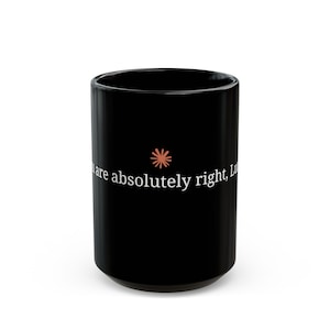 May include: A black ceramic mug featuring a small coral-colored starburst icon centered above the white printed text that reads, "You are absolutely right, Luc". The mug has a smooth, glossy finish and a cylindrical shape with a simple, clean design.