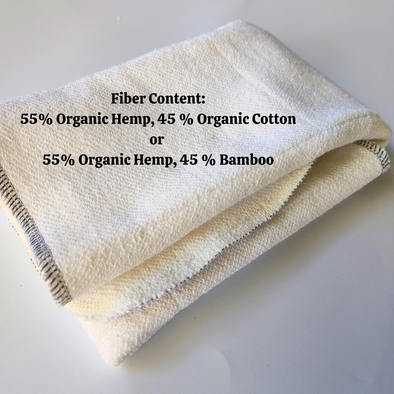 May include: A folded white fabric towel with black text that reads "Fiber Content: 55% Organic Hemp, 45% Organic Cotton or 55% Organic Hemp, 45% Bamboo".