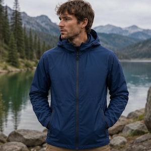 Könnte beinhalten: Eine marineblaue Kapuzenjacke mit durchgehendem Frontreißverschluss, langen Ärmeln mit elastischen Bündchen und zwei Seitentaschen mit Reißverschluss. Die Jacke ist aus einem glatten, einfarbigen Stoff gefertigt und verfügt über eine Kapuze.