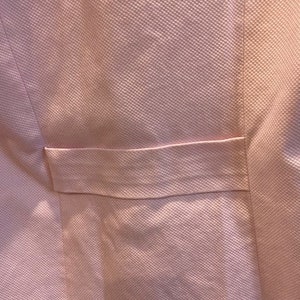 May include: A pale pink fabric with a textured surface and a single pocket.
