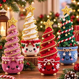 May include: Four crocheted Christmas tree figurines in pink, white, red, and green. Each tree features a yellow star topper, gold bead garland, and a smiling face on its base. The trees are decorated with small bells, bows, and snowflake accents.