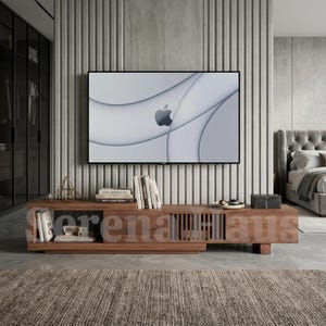 May include: A long, low-profile wooden media console with a natural grain finish, featuring open shelving on the left, a slatted cabinet door on the right, and a flat top surface holding several books and a small geometric metal sculpture.