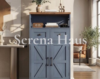 Puede incluir: Un armario de almacenamiento de madera azul con dos cajones superiores con pomos redondos y dos puertas inferiores con refuerzos en forma de X y tiradores verticales. La unidad tiene un estante superior abierto y una superficie de madera.