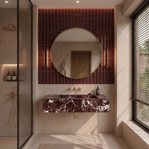 Puede incluir: Un mueble de baño con un lavabo de mármol rojo intenso con vetas blancas, montado sobre una pared de azulejos verticales de color rojo oscuro. Un gran espejo circular con marco dorado cuelga sobre el lavabo, flanqueado por dos luces.