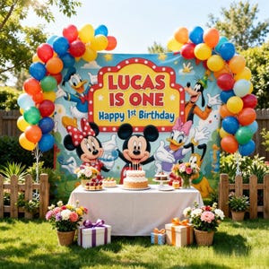 Peut inclure: Une toile de fond pour anniversaire avec Mickey, Minnie, Donald, Daisy, Dingo et Pluto. La bannière indique 'LUCAS IS ONE Happy 1st Birthday'. La scène comprend une table avec un gâteau, des fleurs et des boîtes de cadeaux.