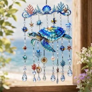May include: A decorative hanging ornament featuring a central sea turtle with a blue and green stained-glass style shell. The piece includes dangling chains adorned with small metal sea creatures, coral, shells, and clear crystal teardrop prisms.