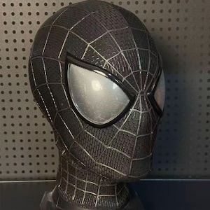 Peut inclure: Un masque intégral noir présentant une texture en forme de briques sur toute la surface avec de fines lignes de toile argentées. Le masque comprend deux grands verres en forme d'amande avec une fine grille en maille argentée sur les ouvertures.