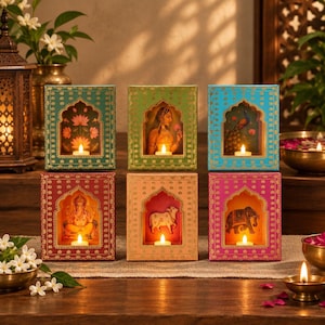 Peut inclure: Six boîtes décoratives rectangulaires disposées sur deux rangées, chacune présentant une découpe en arche affichant une illustration unique et une petite bougie chauffe-plat allumée. Les boîtes sont bleu sarcelle, vert, bleu, rouge, pêche et magenta avec des motifs dorés.