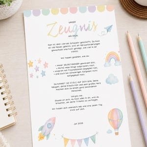 May include: A white rectangular paper certificate titled Unser Zeugnis an dich with pastel watercolour illustrations including a rocket, hot air balloon, rainbow, clouds, and stars. The text is in German, featuring a row of colourful circles at the top.