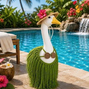 May include: A white goose figurine wearing a straw hat adorned with a pink hibiscus flower and green leaves, and a green crocheted hula skirt with a matching bikini top featuring two brown circular accents, standing on a stone pool deck.