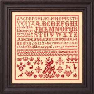 May include: A framed cross-stitch sampler featuring red thread on a light beige fabric. The design includes uppercase and lowercase alphabets, numbers 1 through 15, decorative borders, and various motifs including a peacock, crowns, and animals.