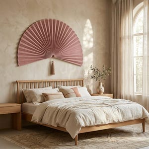 Large dusty rose bamboo wall fan above a bed with text “Make a Statement,” showing its scale as oversized bedroom wall decor.