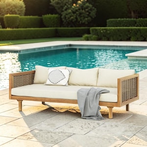 May include: A wooden outdoor daybed featuring a light-colored seat cushion, three back cushions, and woven side panels. One back cushion displays a black and white geometric pattern. A gray throw blanket is draped over the front of the seat.