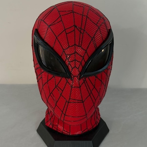 May include: A red full-head mask featuring a black web pattern across the surface. The mask includes large, angular black-rimmed eye lenses with a dark mesh interior, designed to cover the entire head and neck area for a complete character look.