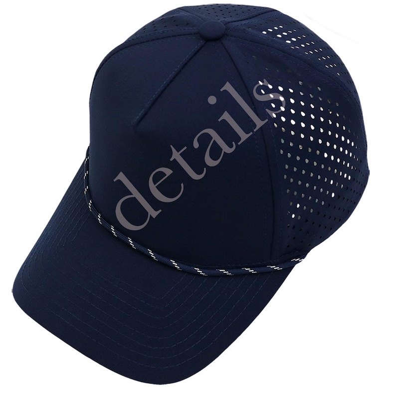K&ouml;nnte beinhalten: Eine marineblaue Baseballkappe mit einer festen Vorderseite und einem perforierten Netzr&uuml;cken zur Bel&uuml;ftung. Eine d&uuml;nne, gedrehte wei&szlig;-marineblaue Kordel verl&auml;uft &uuml;ber der Basis der Krone, direkt &uuml;ber dem gebogenen Schirm. Das Wort details ist sichtbar.