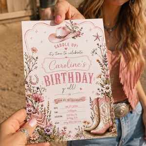 May include: A rectangular birthday invitation card featuring a pink cowboy hat, floral arrangements, a horseshoe, and a pair of pink and white cowboy boots. The text reads: SADDLE UP! it's time to celebrate Caroline's BIRTHDAY y'all! JOIN US TO CELEBRATE!