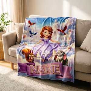 May include: A soft fleece blanket featuring a cartoon princess in a purple dress, a squirrel, a rabbit, and birds against a castle background. A purple banner at the bottom contains the text NAME in gold letters, set against a light blue sky.