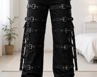 May include: Black cargo pants featuring multiple horizontal straps with silver-toned metal buckles across the front of each leg. The pants include side pockets, hanging fabric straps, and a silver chain detail attached to the front belt loops.