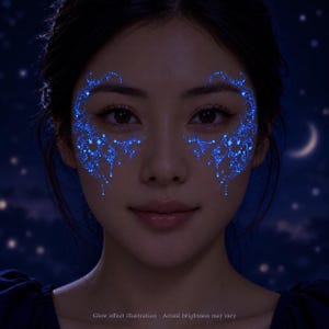 May include: A set of glowing blue temporary face tattoos featuring intricate celestial patterns with stars and crescent moons applied around the eyes. The design emits a bright luminescence against the dark skin. Text reads: Glow effect illustration.