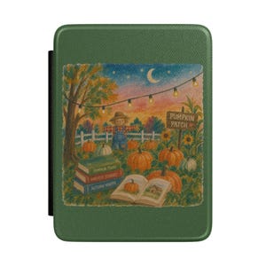Op de afbeelding: Een groene e-readerhoes met een bedrukte illustratie van een vogelverschrikker in een pompoenveld bij schemering. De afbeelding toont lichtsnoeren, een bord met PUMPKIN PATCH en boeken met de titels Pumpkin Tales, Harvest Stories en Autumn Nights.