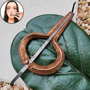 以下が含まれることがあります： クロスハッチ模様が施された銅色の円形テクスチャフレームと、中央の鋼鉄製タングを備えた金属製の口琴。楽器には、演奏している人物を描いた小さな円形のインセットイラストが含まれています。