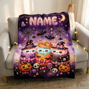 May include: A purple fleece blanket featuring the text NAME at the top, decorated with a Halloween theme including three cute characters in gift boxes, bats, spiderwebs, pumpkins, skulls, candy, stars, and a crescent moon on a starry background.