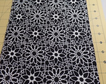 May include: Black fabric with a white geometric pattern of repeating starburst shapes.
