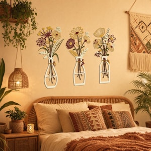 May include: A set of three wall-mounted decorations featuring stylised floral bouquets in white glass-shaped vases. Each piece displays a unique arrangement of flowers in shades of yellow, maroon, and white with green stems and leaves.