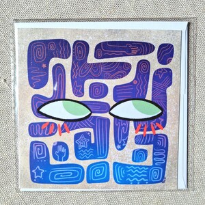 May include: A square greeting card featuring a tan background with a central abstract design of interconnected blue and purple shapes. The design includes white and red line patterns, stars, and hand icons, with two large green eyes and red lashes.