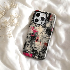 Könnte beinhalten: Eine Smartphone-Hülle mit einem mehrschichtigen Collage-Design aus schwarzen, weißen und roten abstrakten Graffiti-Markierungen, Tintenspritzern und abgenutzten Texturen. Die Hülle hat eine rechteckige Form mit abgerundeten Ecken und Kameraaussparung.