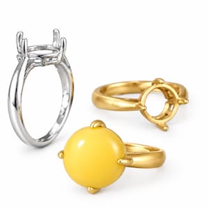 May include: Three rings are displayed: one polished silver-tone ring setting with four prongs, one matte gold-tone ring setting with four prongs, and one gold-tone ring featuring a smooth, round, opaque yellow cabochon stone set in four prongs.