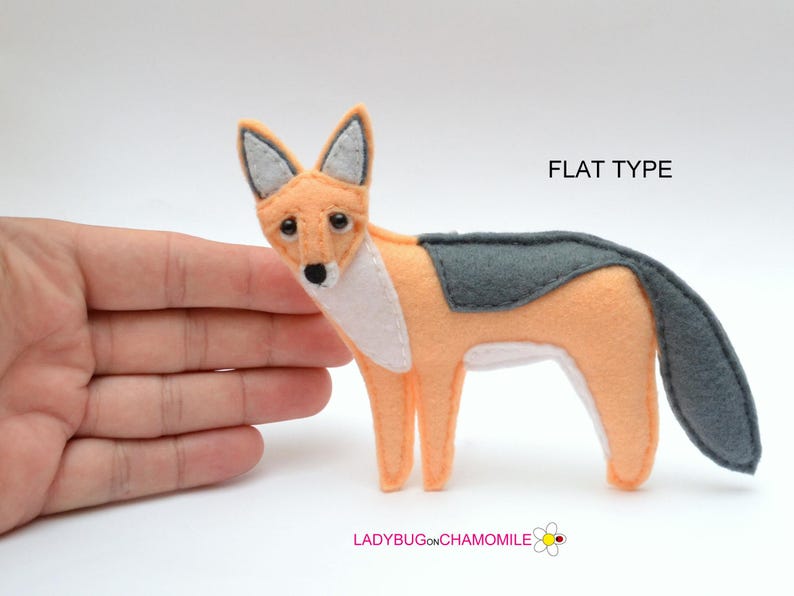 May include: A flat felt fox ornament in peach and dark gray with white chest detailing. The fox has black eyes and a black nose. The text FLAT TYPE is printed in the upper right corner, and LADYBUGONCHAMOMILE is printed at the bottom.