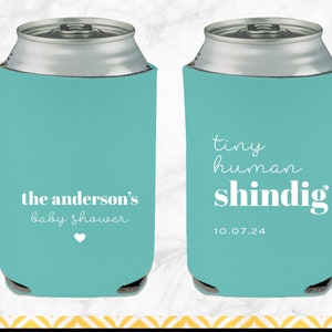 May include: Two turquoise blue can coolers with white text. One cooler says "the anderson's baby shower" with a small white heart. The other cooler says "tiny human shindig" with the date "10.07.24".