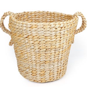 May include: A light tan woven basket featuring a tapered cylindrical body with a braided texture and two thick, twisted rope handles attached to the sides. The basket is constructed from natural dried plant fibres with a consistent weave pattern.