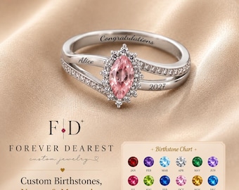 May include: A silver-toned ring featuring a marquise-cut pink center stone surrounded by small clear stones. The band is engraved with the text Congratulations, Alice, and 2027. A birthstone chart is visible in the corner with twelve colored stones.