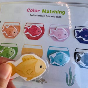 Close-up of a color matching activity page where a child is placing a fish cutout into the correct colored fishbowl.