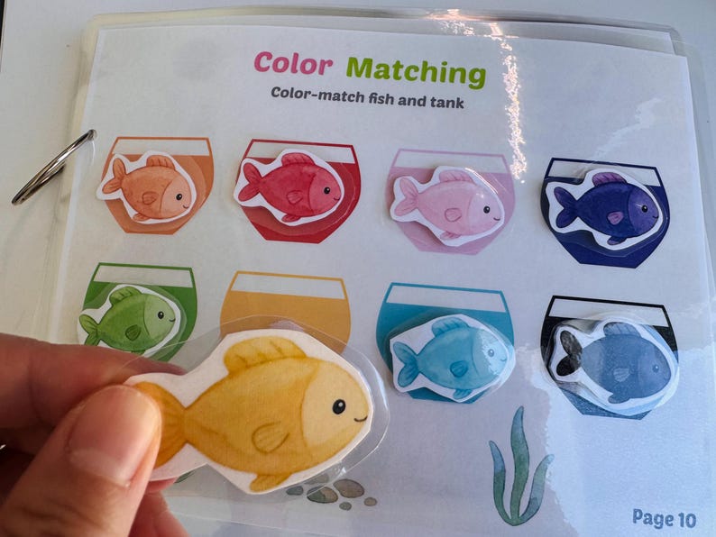 Close-up of a color matching activity page where a child is placing a fish cutout into the correct colored fishbowl.