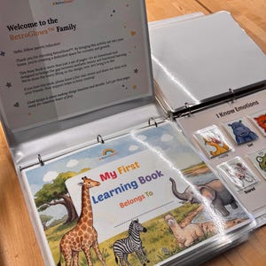 May include: A white three-ring binder containing educational activity pages. The cover features a colorful illustration of a giraffe, zebra, and llama in a landscape with the text My First Learning Book. An emotion chart shows animal icons.
