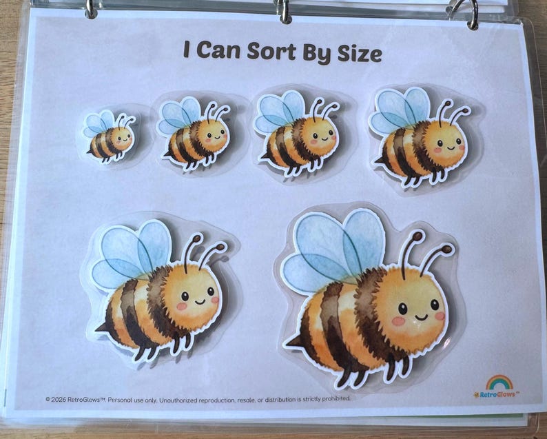 May include: A learning activity sheet titled I Can Sort By Size featuring six cartoon bee illustrations of varying sizes. Each bee has yellow and brown stripes, light blue wings, and a smiling face. The sheet includes the text 2026 RetroGlows.