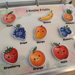 May include: A laminated educational sheet titled I Know Fruits featuring colorful cartoon stickers of a peach, banana, pineapple, grape, mango, blueberry, strawberry, orange, apple, and pear, each labeled with its corresponding name in black text.