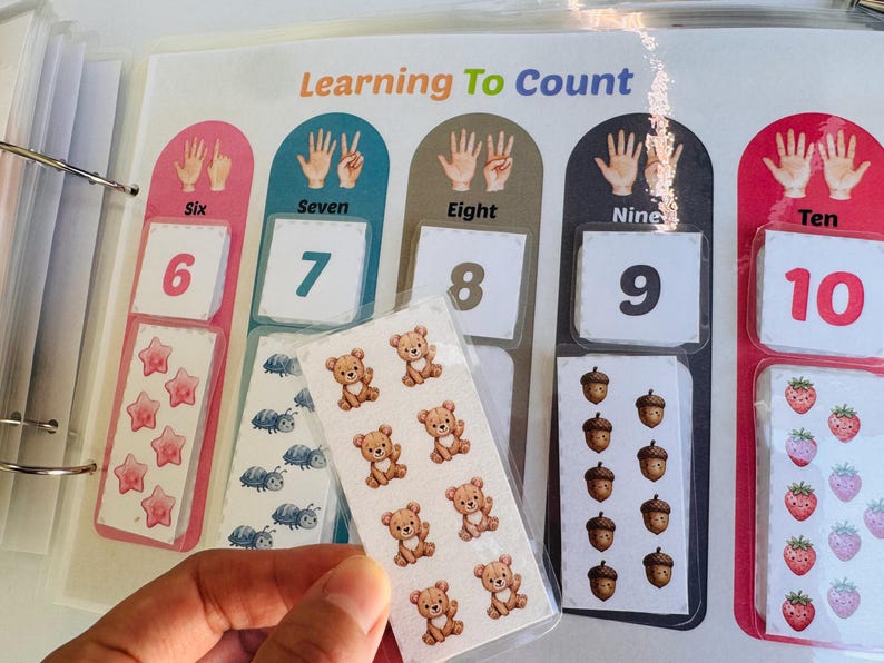 Counting activity page "Learning To Count" from 6 to 10, showing a child's hand matching number-themed cutouts.