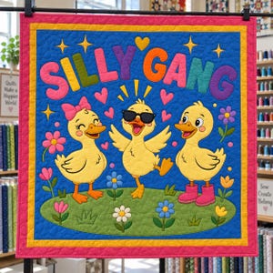 以下が含まれることがあります： カラフルな文字で「SILLY GANG」と書かれた正方形の布製壁掛け。3羽の黄色いアヒルの子が花のある緑の場所に立っています。左のアヒルはピンクのリボン、中央のアヒルは黒いサングラス、右のアヒルはピンクのブーツを履いています。背景は青色で、黄色い星とピンクのハートが描かれています。