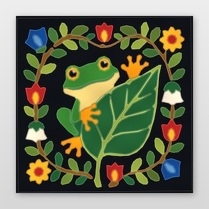 May include: A square textile wall hanging featuring a green frog with orange feet peeking from behind a large green leaf. The frog is centred within a circular wreath of green vines, colourful flowers, and leaves against a solid black background.