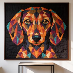 May include: A square wall hanging featuring a geometric, multi-coloured dog portrait constructed from fabric patches. The dog face is composed of triangular shapes in orange, purple, teal, and brown, set against a solid black background.