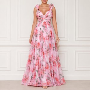 Peut inclure: Une robe longue sans manches avec un imprimé floral rose et rouge vif sur fond rose clair. La robe présente un décolleté en V profond, de larges bretelles à volants, un corsage ajusté avec un design croisé et une jupe longue et ample.