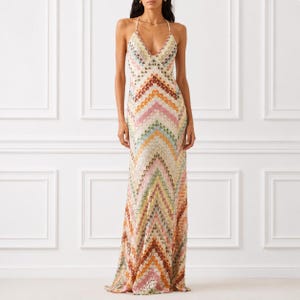 Peut inclure: Une robe longue sans manches avec un décolleté en V et de fines bretelles. Le vêtement présente un motif chevron multicolore dans des tons orange, rose, jaune, vert et bleu, intégré dans un tissu en maille texturée sur toute la longueur.