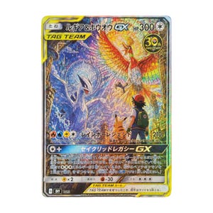 以下が含まれることがあります： ルギアとホウオウがステンドグラス風に描かれたトレーディングカード。下部にはトレーナーとピカチュウが立っている。カードには「ルギア＆ホウオウGX」、「HP300」、および日本語のテキストが全体にデザインされている。