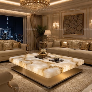 Op de afbeelding: Een grote, vierkante salontafel met een dik, doorschijnend blad van crèmekleurige steen met gouden aders die warm oplicht, rustend op een platte, goudkleurige metalen voet in een woonkamer met beige banken en uitzicht op de stad.