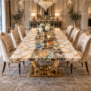 May include: A rectangular dining table featuring a surface made of inlaid multicolored agate slices with a polished finish, supported by a large, circular gold-toned metal base, surrounded by six beige tufted upholstered dining chairs.